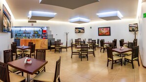 A restaurant with multiple tables and chairs, a bar area, and artwork on the walls.
