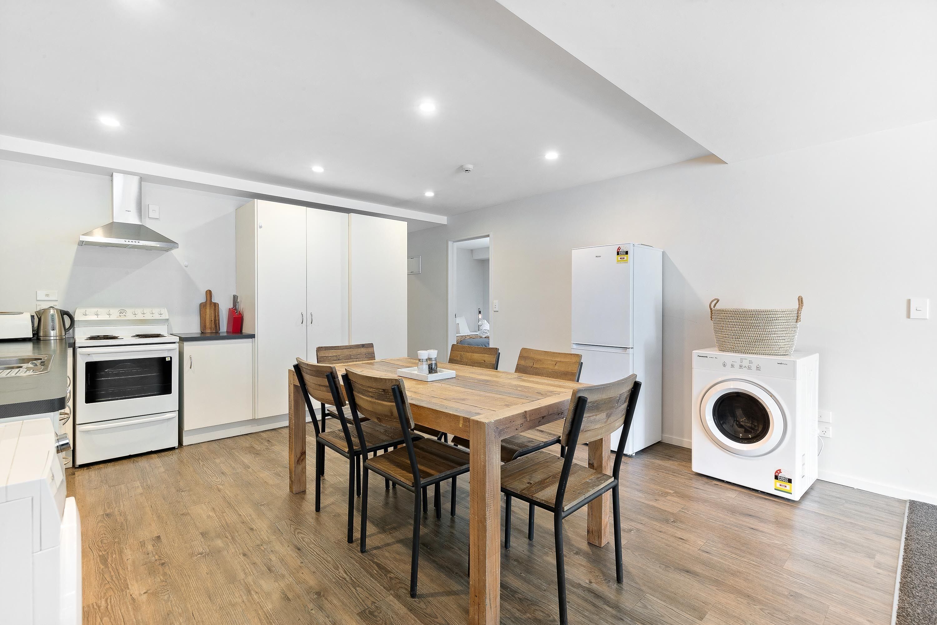 Une cuisine moderne équipée d’une table à manger, de chaises, d’un lave-linge et d’un réfrigérateur.