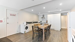 A modern kitchen with a wooden dining table, built-in appliances, and a washing machine. - Central Mountain View Paradise (Queenstown)