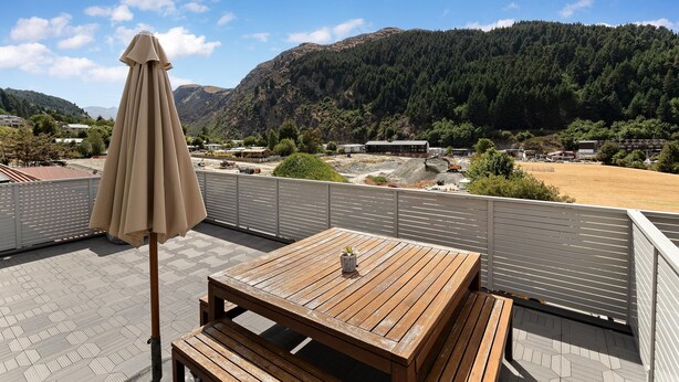 A wooden deck with a table and benches, overlooking a mountainous landscape with a clear sky. - Central Mountain View Paradise (Queenstown)