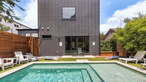 A modern building with a pool and lounge chairs. - Downtown Luxury Oasis - Heated Pool - 5 Bedrooms (Austin)