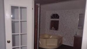 A bathroom with a bathtub, a vanity with a mirror, and a small window above the sink. - Excellent Recreational Farm Minutes from DineyWorld (Frostproof)