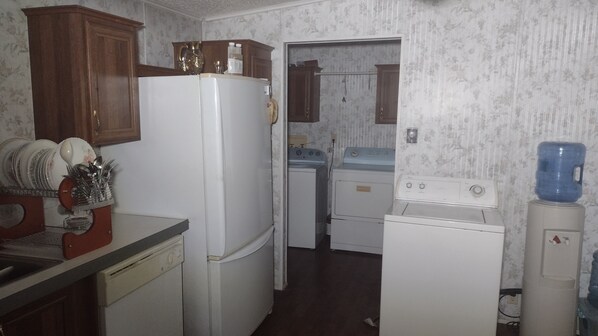A compact kitchen with a refrigerator, washing machine, and a sink.