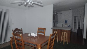 A dining room with a wooden table and chairs, a ceiling fan, and a kitchen area visible through an open doorway. - Excellent Recreational Farm Minutes from DineyWorld (Frostproof)