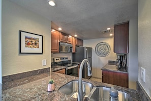 A modern kitchen with granite countertops, stainless steel appliances, and wooden cabinets.