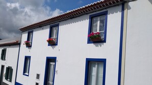 A building with white walls and blue trim, featuring multiple windows and a door.
