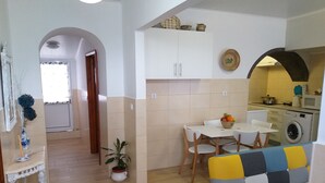 A compact living space with a dining area, a sofa, a kitchen, and a laundry area.