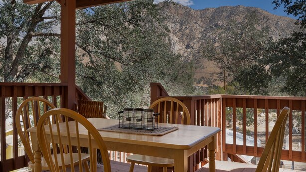 Eine Holzterrasse mit Tisch und Stühlen mit Blick auf eine gebirgige Landschaft.