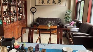 A traditional Japanese room with tatami flooring, a tatami mat table, a wooden cabinet, a leather sofa, and a large calligraphy piece on the wall. - Jingyue Boutique Hotel (Linyi Olympic Sports Center Store) (Linyi)