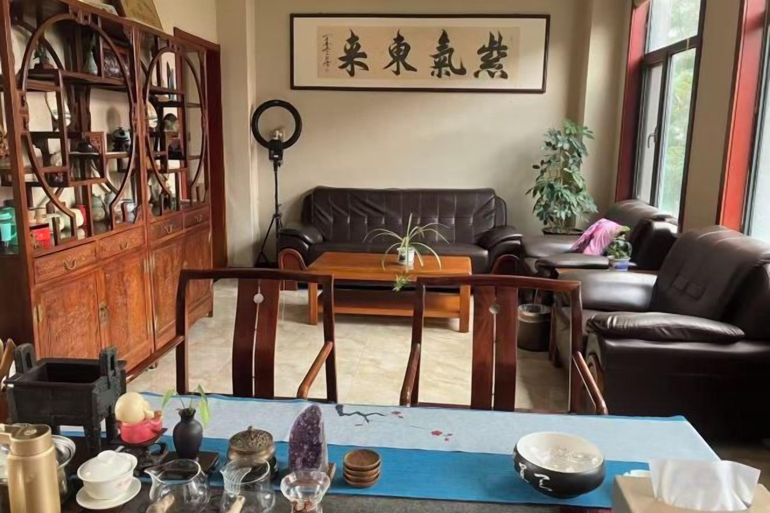 Quarto tradicional com um armário de madeira, um sofá, uma mesa de jantar com louças e um vaso de plantas.