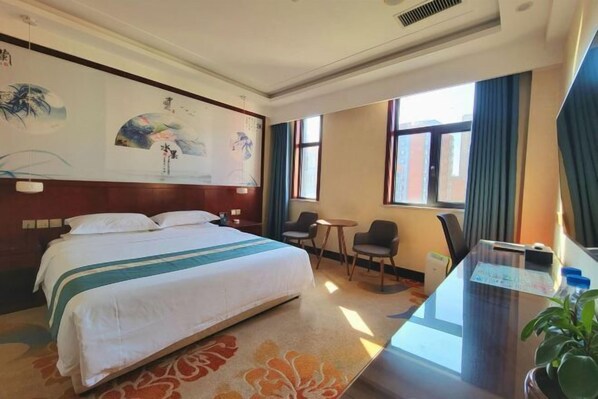 Relax in a spacious room with a large bed, traditional artwork, and a desk for work.