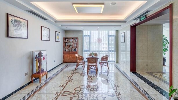 A hotel lobby with a marble floor, a reception desk, framed artwork on the walls, and a large window. - Jingyue Boutique Hotel (Linyi Olympic Sports Center Store) (Linyi)