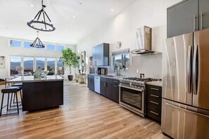 Enjoy cooking in this spacious kitchen with a central island, stainless steel appliances, and a large window offering a view of the outdoors.