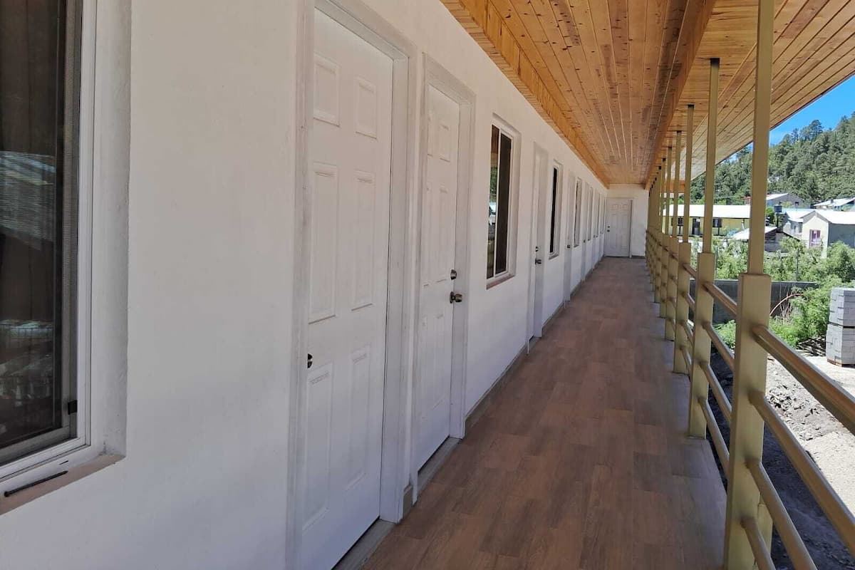 A corridor with white doors and windows, wooden flooring, and a wooden ceiling.