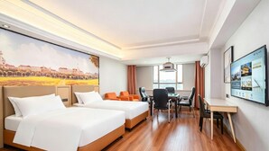 A hotel room with two beds, a desk, chairs, a large window, and a wall-mounted TV.