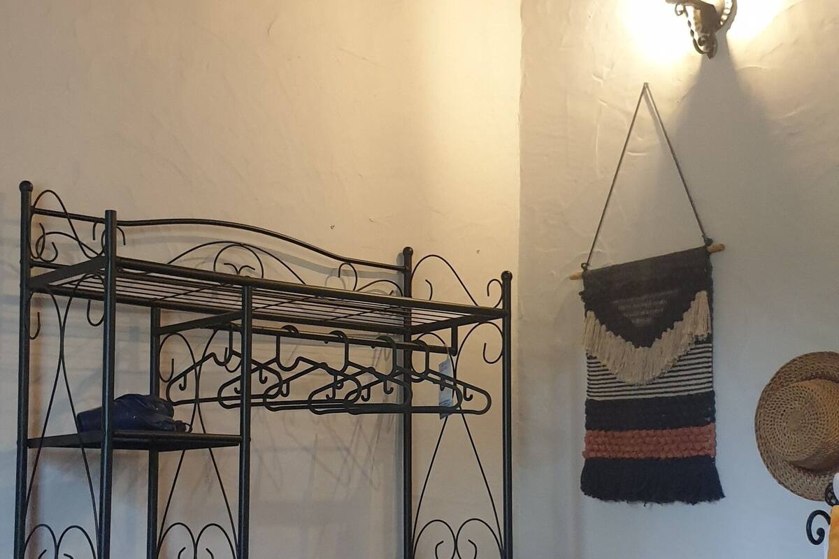 Une pièce avec un lit superposé, une décoration murale en macramé et un panier tressé placé sur le côté droit.