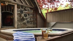 A stone wall, a wooden deck, a hot tub, and a stack of towels.