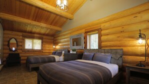 A log cabin bedroom with two beds, a large mirror, and a wooden ceiling.