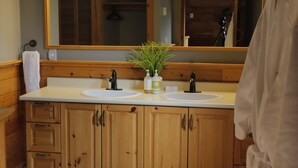 A bathroom with wooden cabinets, a white sink, and a large mirror with lights.