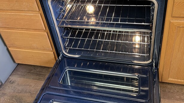 Een keuken met een ingebouwde oven, een kookplaat en houten kastjes.