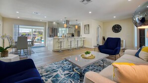 A modern living room with a dining area, kitchen, and a large window. - VRCC Villa San Miguel (Cape Coral)