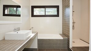 Une salle de bain moderne avec un lavabo blanc, une baignoire et une douche.