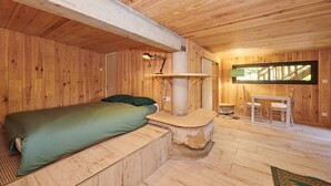 L’intérieur d’une cabane en bois, avec un lit, un bureau et une fenêtre.