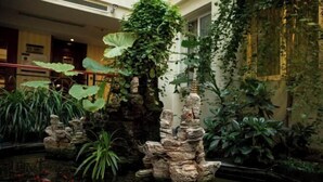 A serene indoor garden with a koi pond, lush greenery, and a stone sculpture. - Yifeng Hotel (Wenli College Honghe Campus Store) (Chongqing)
