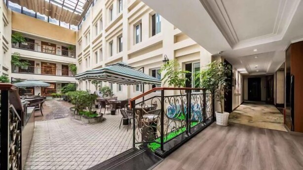 A multi-level atrium with outdoor seating, a staircase, and a glass ceiling. - Yifeng Hotel (Wenli College Honghe Campus Store) (Chongqing)