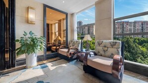 A modern hotel room with a large window offering a city view, a seating area with a sofa and chairs, and a potted plant. - Yifeng Hotel (Wenli College Honghe Campus Store) (Chongqing)