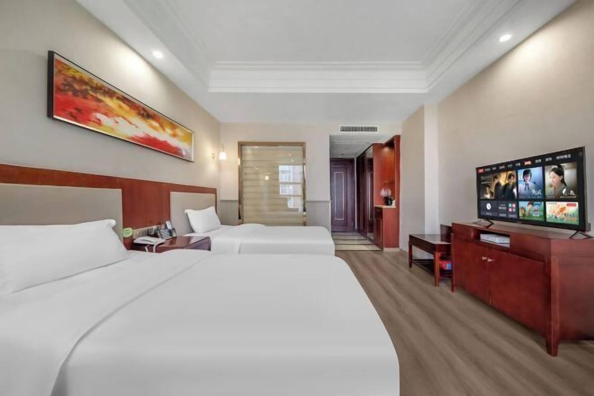 A hotel room with two beds, a TV, and a desk with a computer.