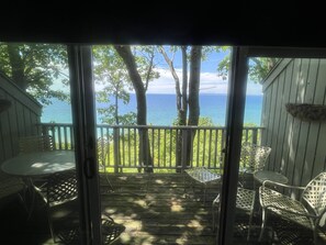Eine Holzterrasse mit Blick auf den Ozean, ausgestattet mit einem Tisch und Stühlen.