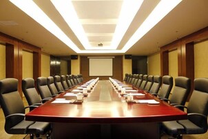 A conference room with a long table, multiple chairs, a projector screen, and a presentation screen.
