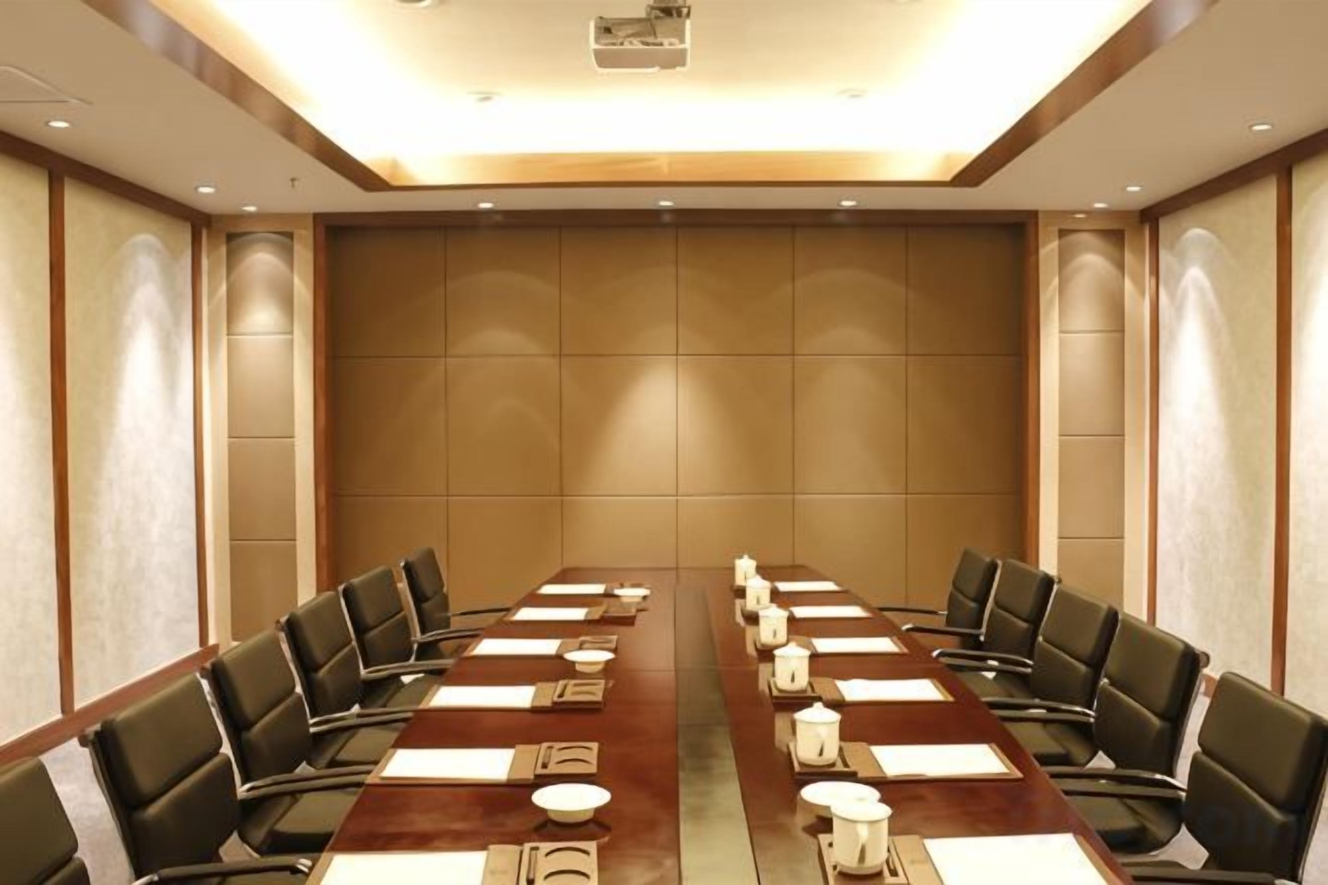 Una sala conferenze con un lungo tavolo, sedie e uno schermo per proiezioni.