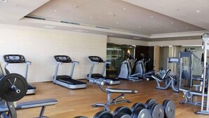 Ein Fitnessraum mit Laufbändern, Crosstrainern und Gewichten.