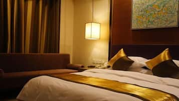 A hotel room with a bed, a sofa, a lamp, and a painting on the wall.