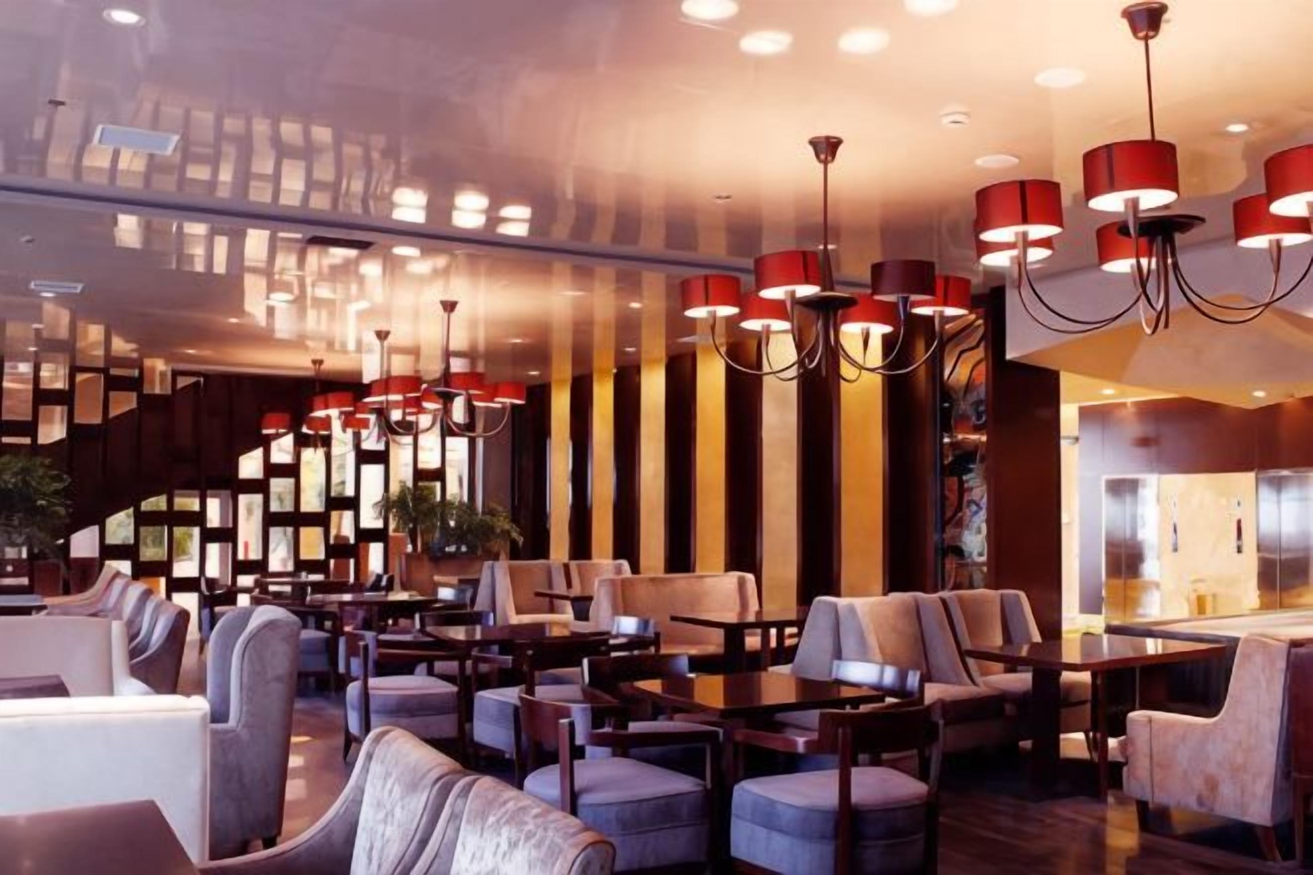 A modern interior with multiple seating areas, including sofas and tables, and a staircase leading to an upper level.