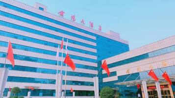 A modern building with multiple flags, large windows, and a clear sky.