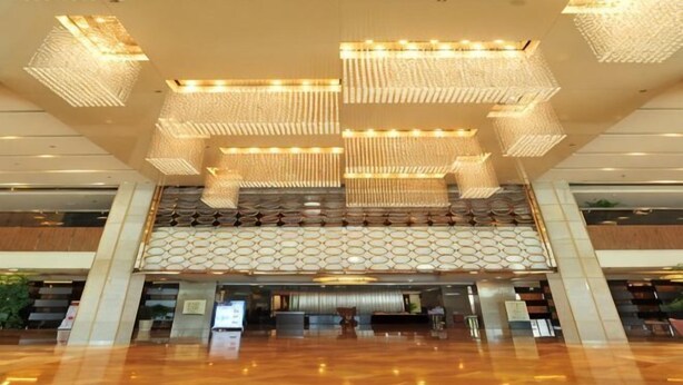 Eine großzügige Lobby mit hoher Decke, mehreren Kronleuchtern und einem strukturierten Wanddesign.