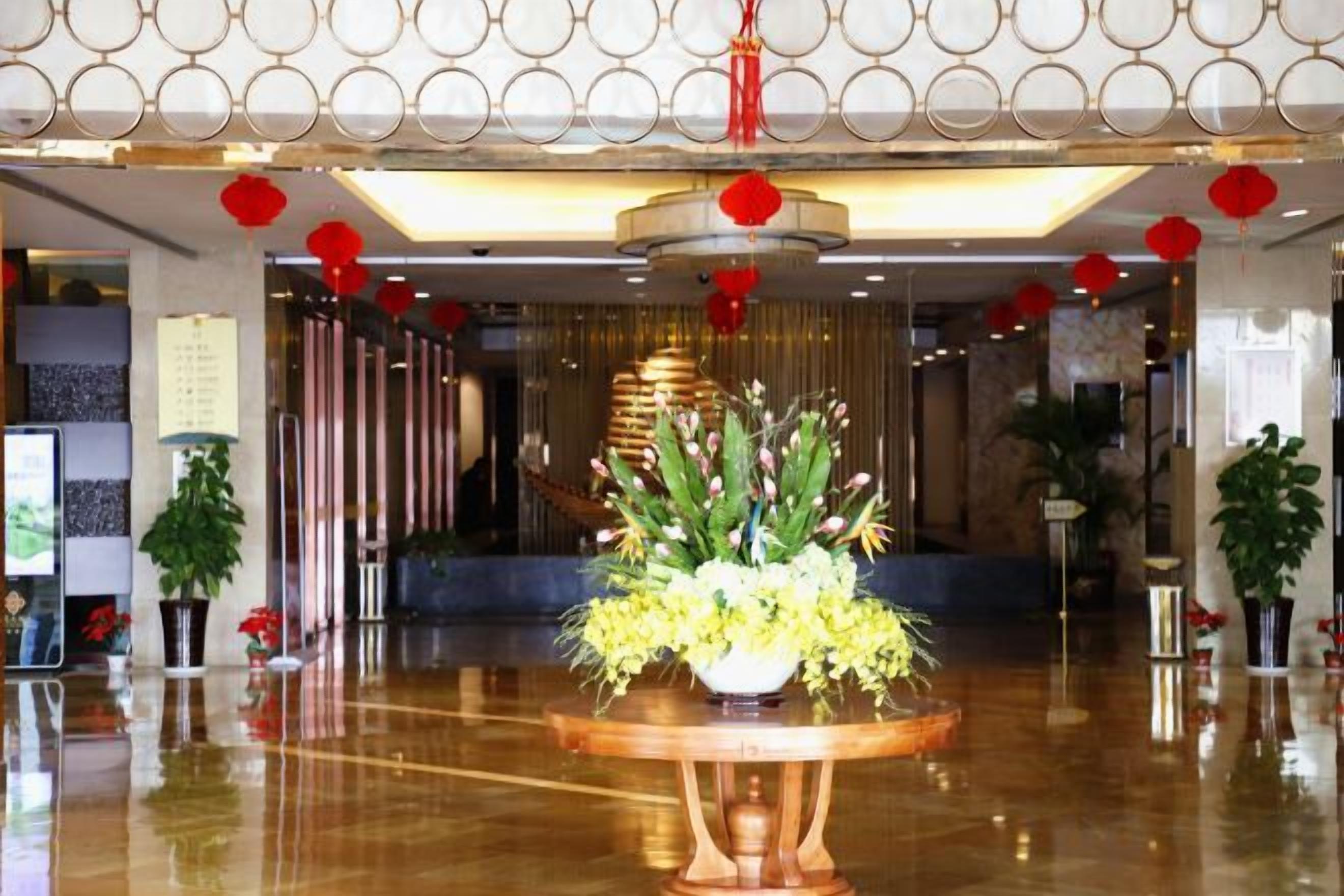 A lobby with a polished floor, a central floral arrangement, and red lanterns.