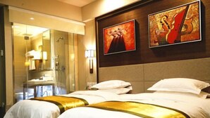 Ein Hotelzimmer mit zwei Betten, einer Dusche und Bildern an der Wand.