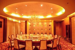 A conference room with a round table, chairs, a chandelier, and a patterned wall.