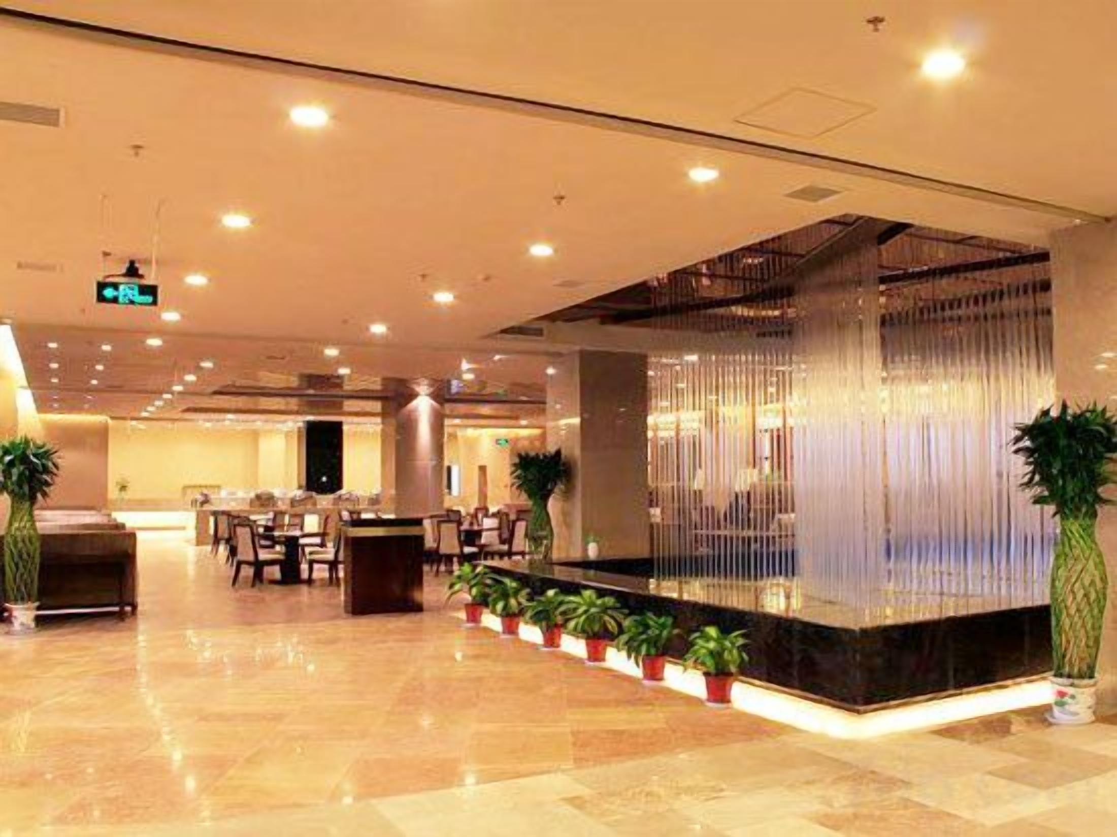 Un'ampia hall con reception, zona salotto e piante in vaso.