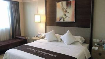 A hotel room with a large bed, a bedside table, a lamp, a painting on the wall, and a window with curtains.