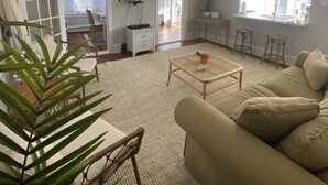 En stue med en beige sofa, et sofabord og et fjernsyn monteret på væggen.