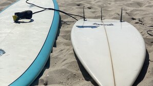 To surfbræder på en sandstrand med havet i baggrunden.