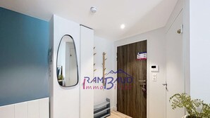 A modern hallway with white walls, a wooden door, and a mirror.