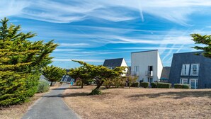 A residential area with modern houses, a paved path, and a clear blue sky. - 200m de la Plage | Apt Cosy pour 3 + Terrasse (Guidel)
