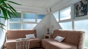 A cozy room with two beige sofas, a small round table, and a lamp. - 200m de la Plage | Apt Cosy pour 3 + Terrasse (Guidel)