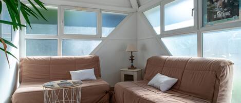 Een knus vertrek met twee beige banken, een kleine ronde tafel en een lamp.
